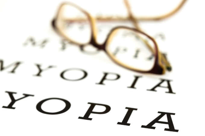 Okulary na tablicy do badania wzroku. Napis miopia. 
